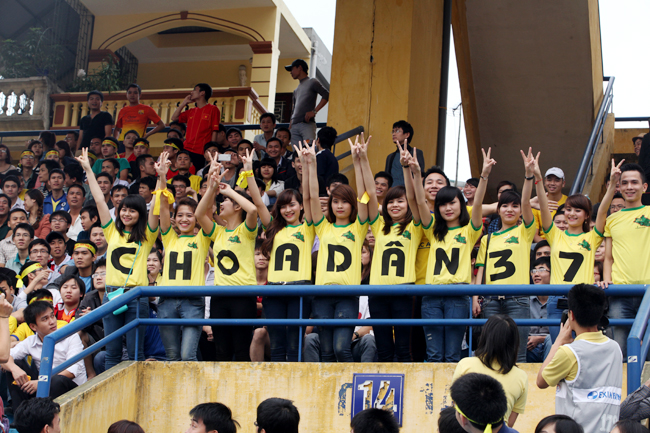 Các nữ cổ động viên xinh đẹp đồng phục vẫy tay chào trước trận đấu với khẩu hiệu trên áo: 'Choa dân 37'.